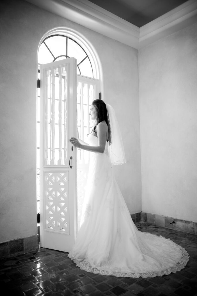 bride getting ready by arched window at Powel Crosley Estate Sarasota black and white portrait