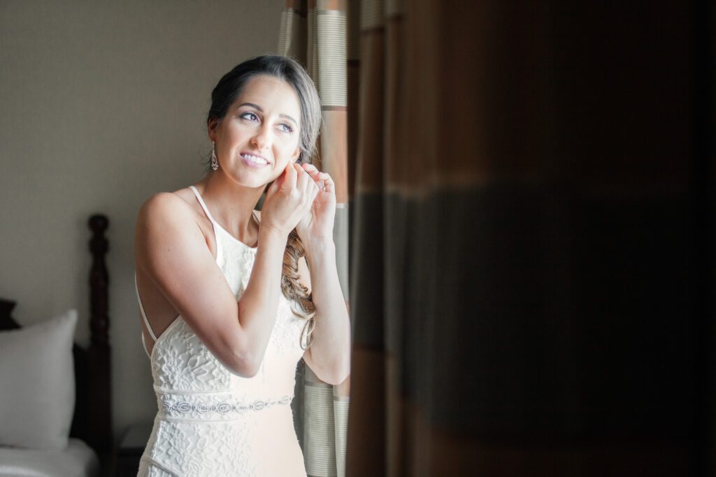 Bride putting on earrings by window at Museum of Fine Arts St. Petersburg wedding