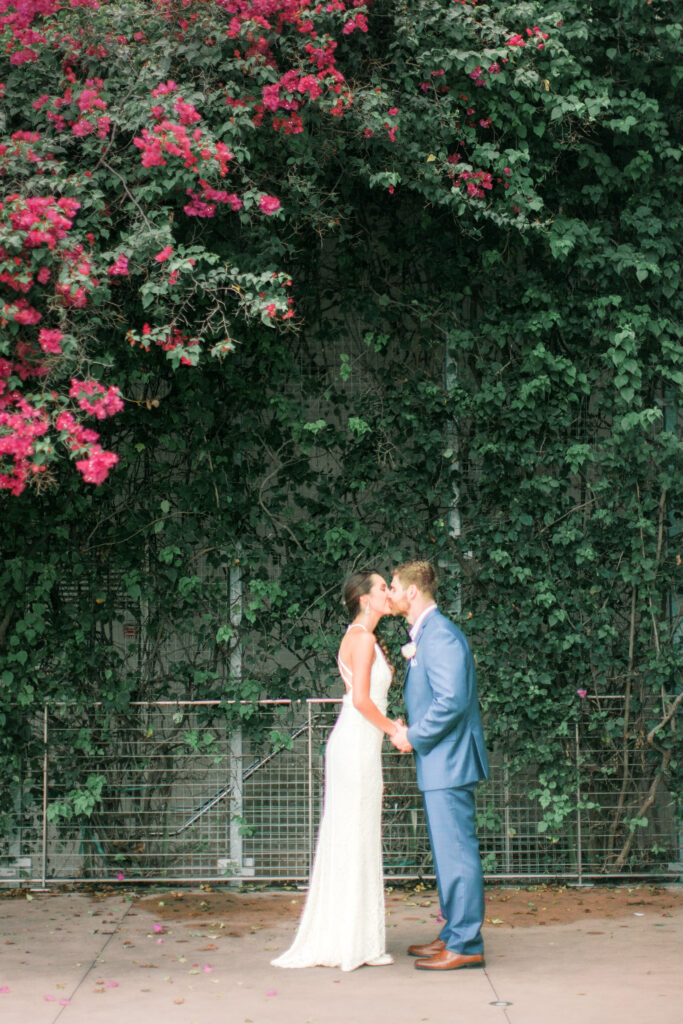 Bride and groom kissing under pink bougainvillea at St. Petersburg wedding venue