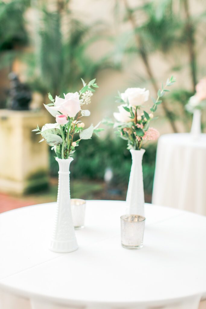 Floral table details with white vases at St. Petersburg courtyard wedding reception