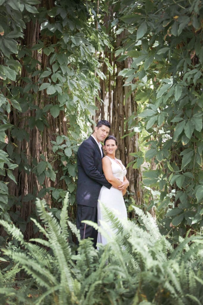 Bride and groom portrait framed by lush greenery and vines at The Ringling Museum gardens in Sarasota