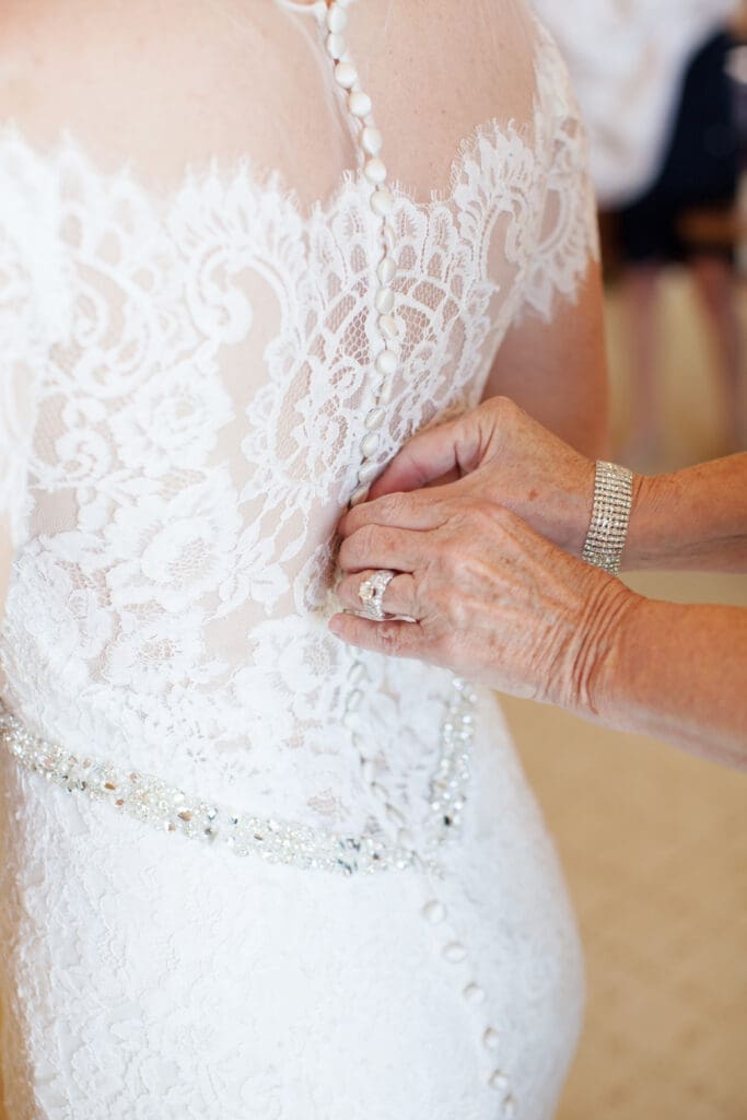 Bride getting into lace wedding gown before ceremony in Hilton Head
