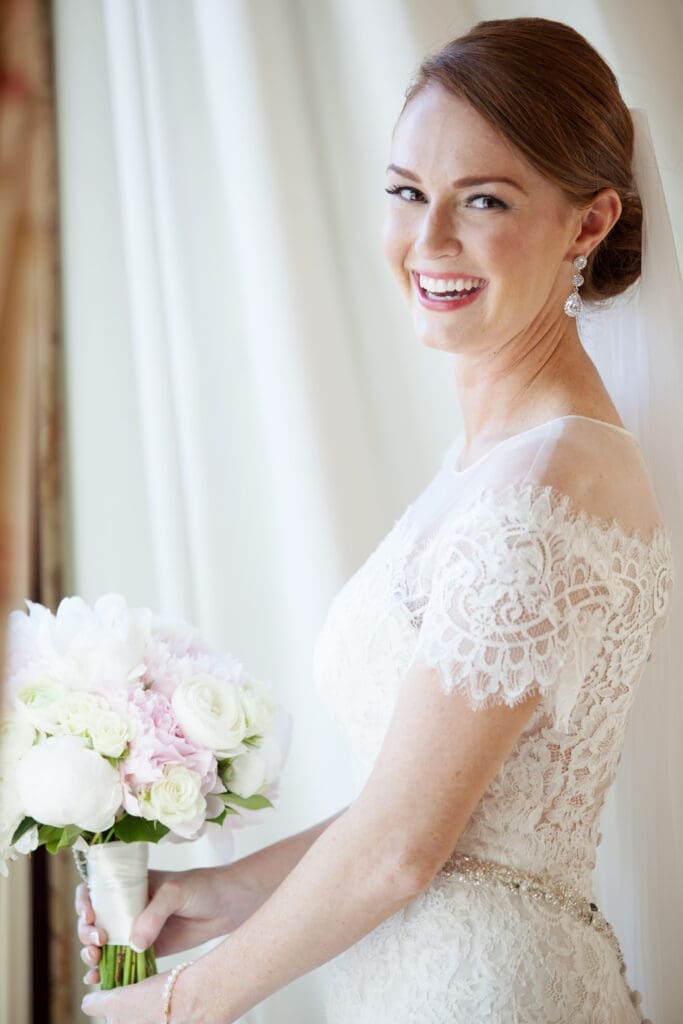 Bride standing near window in soft natural light before wedding ceremony