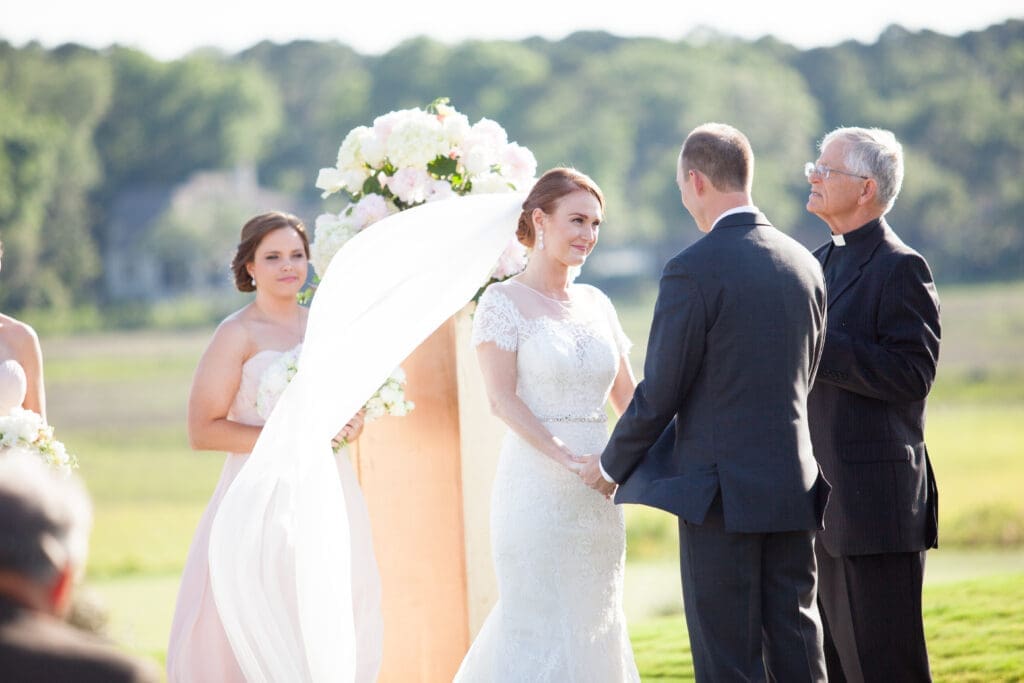 Bride and groom standing together during outdoor waterfront ceremony
