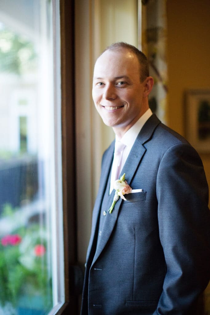 Groom portrait beside window before Southern coastal wedding ceremony