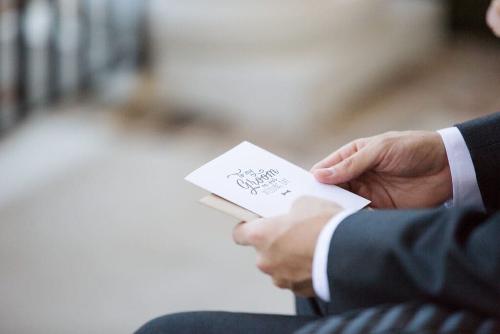 Groom reading handwritten letter before wedding ceremony