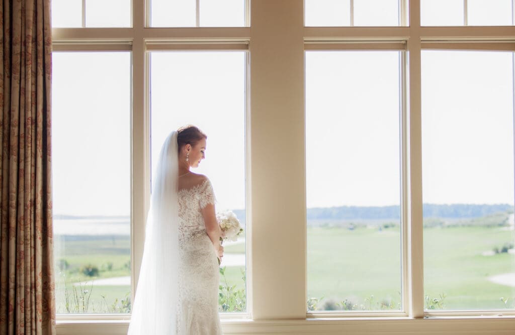 Bride standing in front of large estate windows at Hilton Head wedding venue